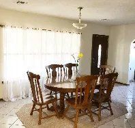 A dining room with a table and chairs in front of a window.