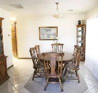 A dining room with a table and chairs and a picture on the wall.