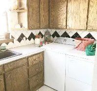 A kitchen with a sink , washer and dryer , and wooden cabinets.