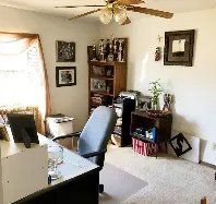 There is a ceiling fan in the room with a desk and chair.