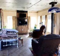 A living room with a bed , chairs , and a television.