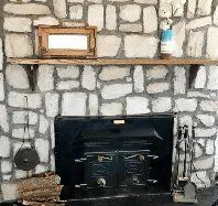 There is a fireplace in the middle of a stone wall.