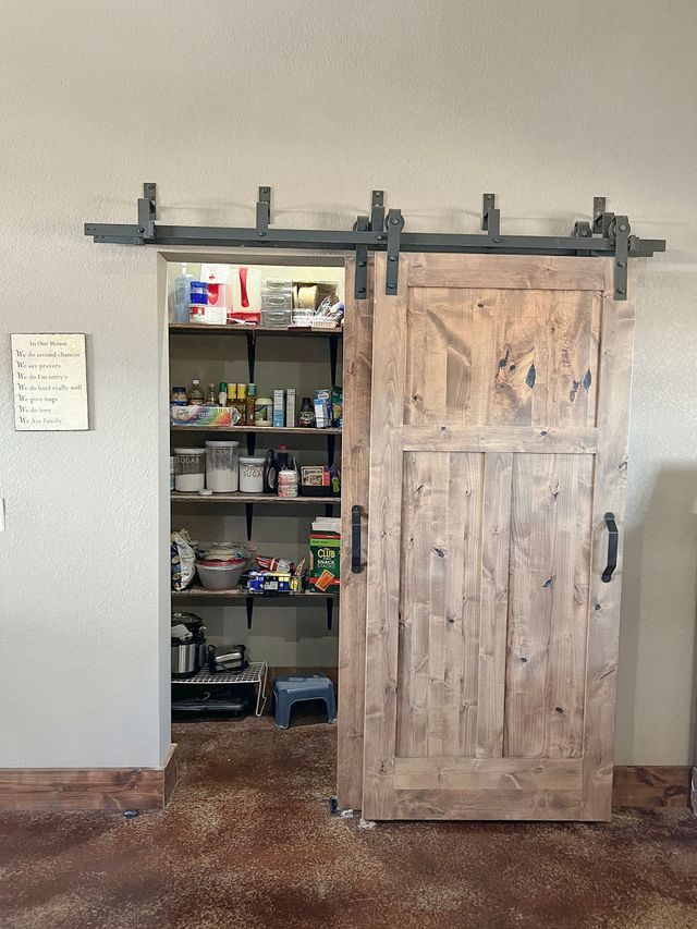 A sliding barn door is open to a pantry filled with food.