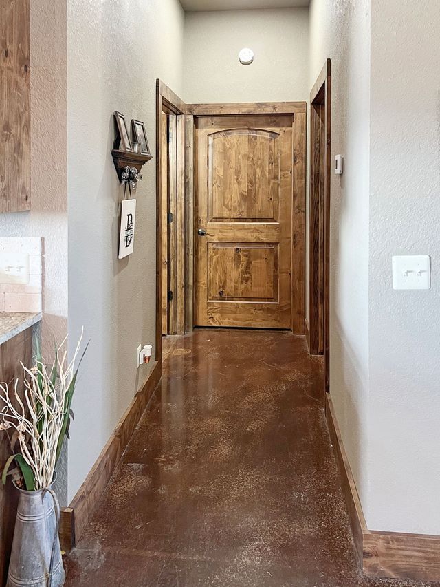 A hallway with a wooden door and a concrete floor