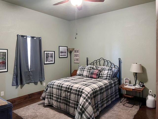 A bedroom with a bed , nightstand , lamp and ceiling fan.