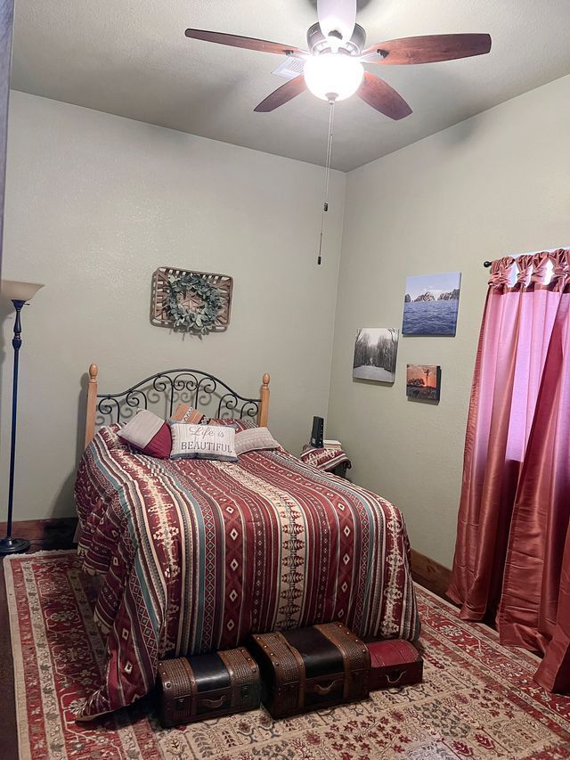 A bedroom with a bed and a ceiling fan