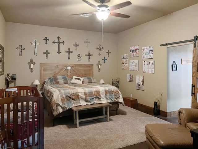 A bedroom with a large bed , a crib and a ceiling fan.