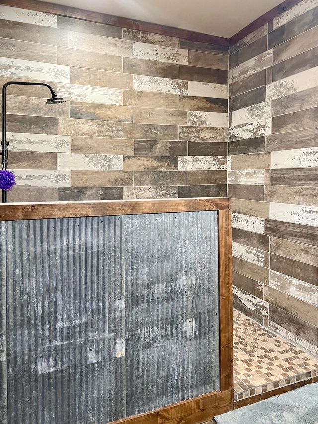 A bathroom with a walk in shower and a metal wall.