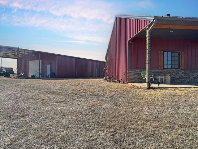 A red barn with a porch and a truck parked in front of it.