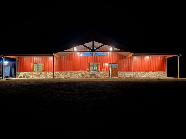 A large red building with a porch is lit up at night.
