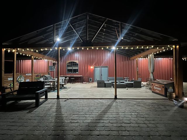 A large covered patio with a lot of furniture and lights at night.