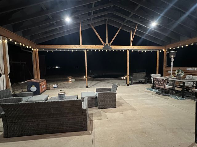 A large patio area with a couch , chairs , and a table at night.
