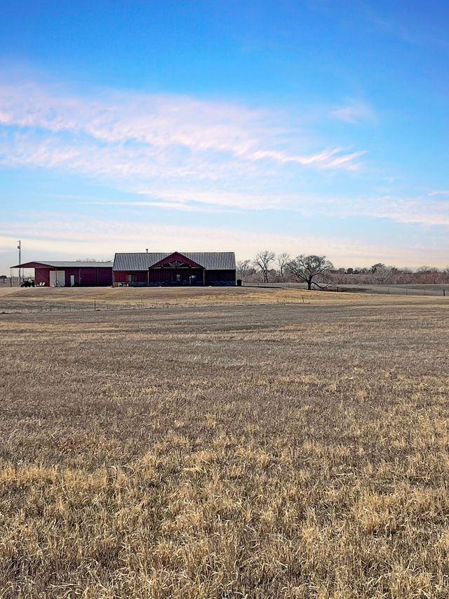 A large dry grass field with a red barn in the background.