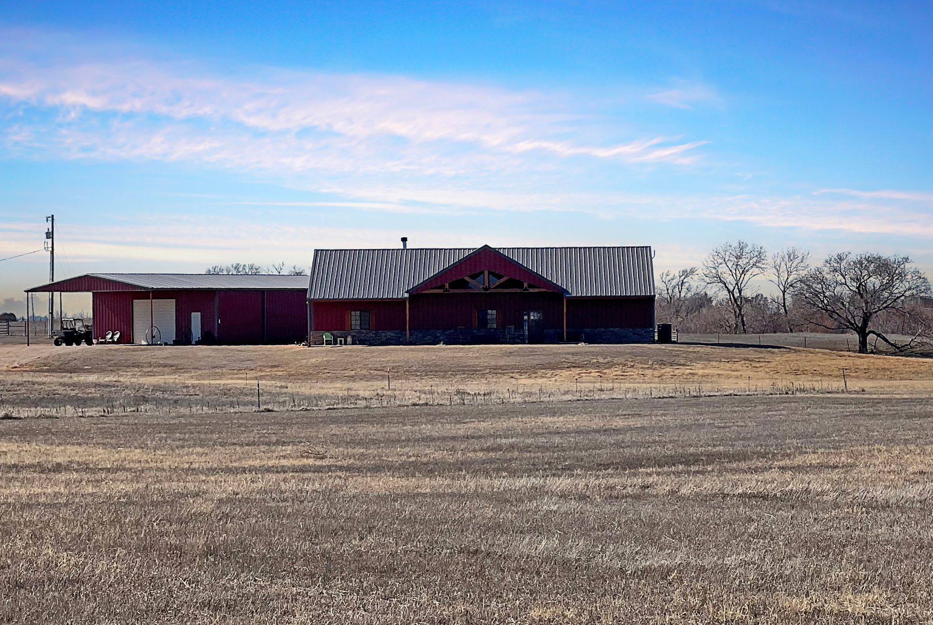 A red barn is sitting in the middle of a dry field.