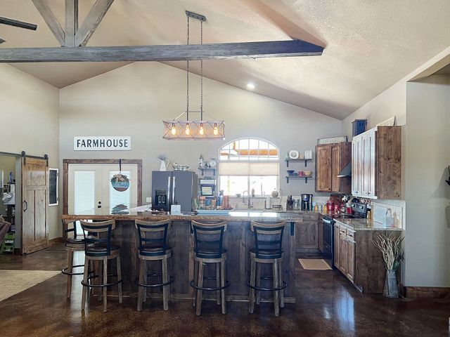 A kitchen with a large island and stools and a sign that says farmhouse