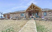 A large stone house with a wooden porch and a walkway leading to it.