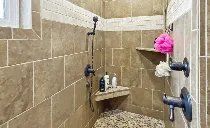 A bathroom with a walk in shower and a sponge on the wall.