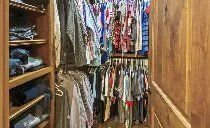 A walk in closet filled with lots of clothes hanging on racks.
