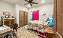 A bedroom with a bed , table , chairs and a ceiling fan.