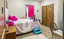 A bedroom with a bed , desk , chair and pink curtains.