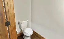 A white toilet is sitting in a bathroom next to a wooden door.