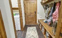 A hallway with a wooden door and a wooden bench.