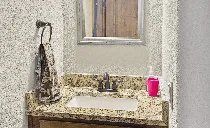A bathroom with a sink , mirror and towel rack.