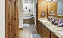 A bathroom with two sinks , a tub and a mirror.