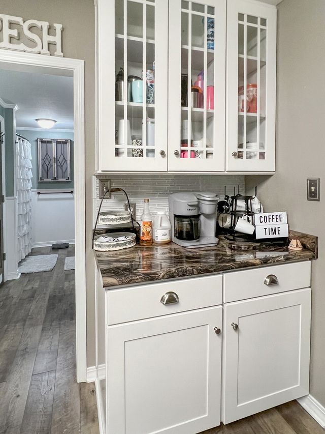 A kitchen with white cabinets , granite counter tops , and a coffee maker.