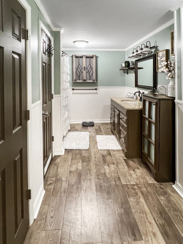 A bathroom with two sinks , a mirror , and hardwood floors.