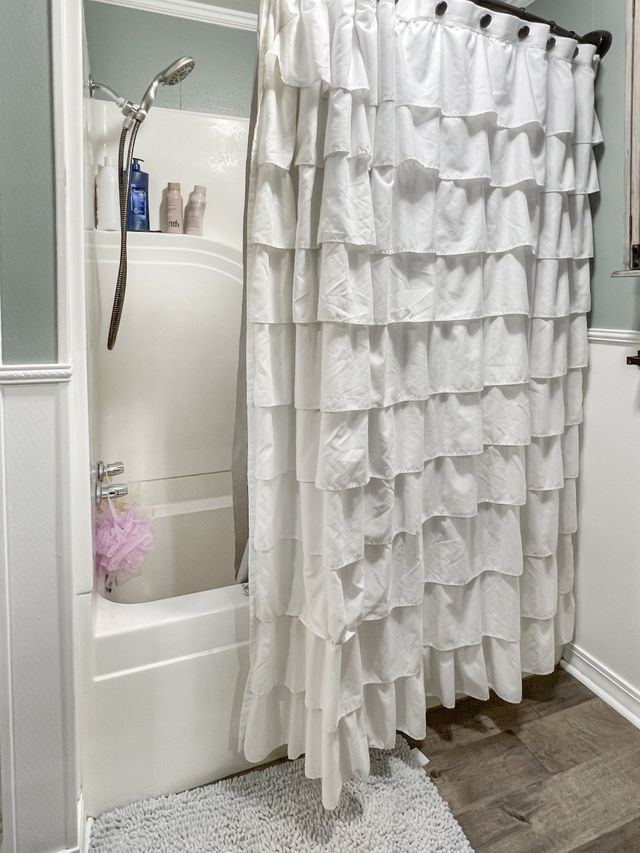 A bathroom with a white shower curtain and a bathtub.