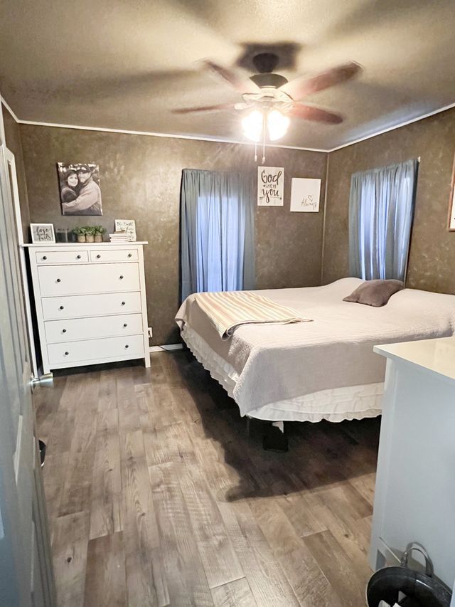 A bedroom with two beds , a dresser , and a ceiling fan.