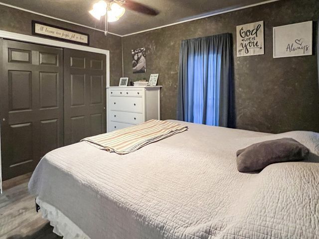 A bedroom with a large bed , dresser , and a ceiling fan.
