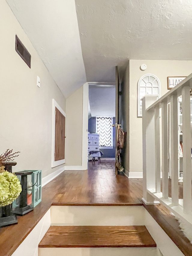 A hallway with wooden stairs leading up to a living room.
