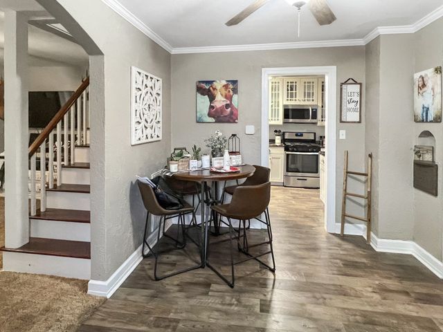 A dining room with a table and chairs and a cow painting on the wall