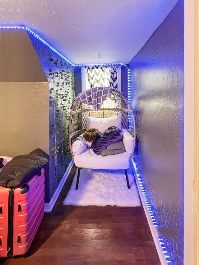 A person is laying in a chair in a bedroom next to a suitcase.