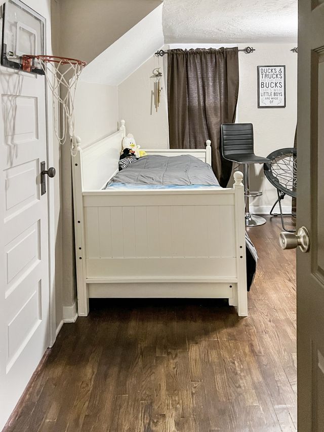 A bedroom with a bed , chair , and basketball hoop.