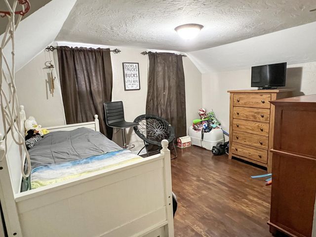 A bedroom with a bed , dresser , chair and television.