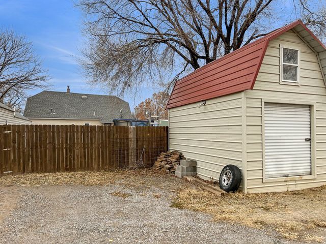 A shed with a red roof is in the backyard of a house.
