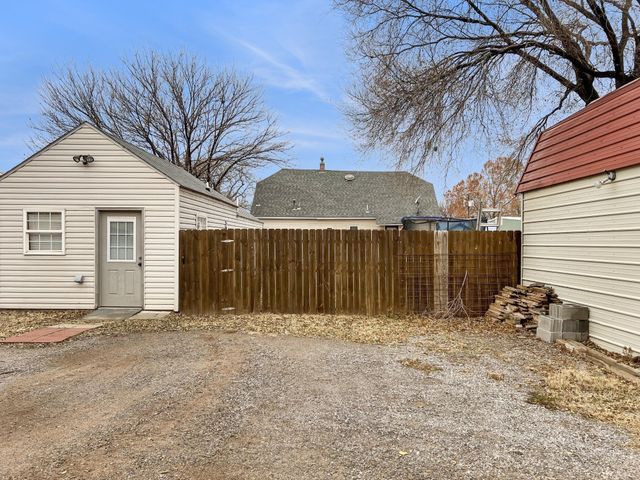 A small white house with a wooden fence in front of it.