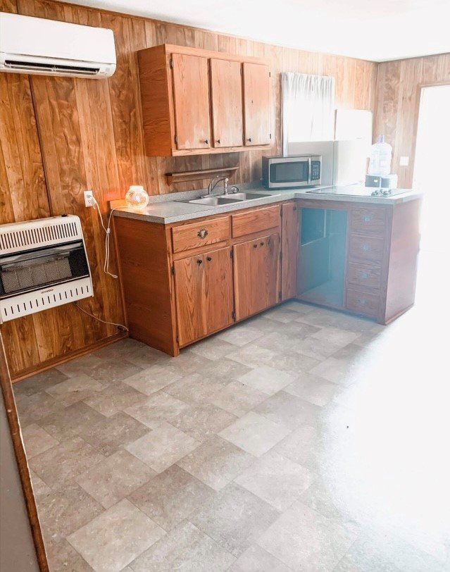 A kitchen with wooden cabinets , a microwave , and a stove.