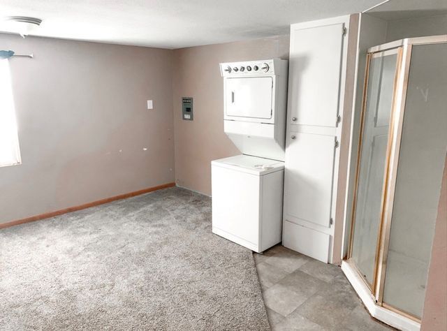 An empty room with a washer and dryer and a shower