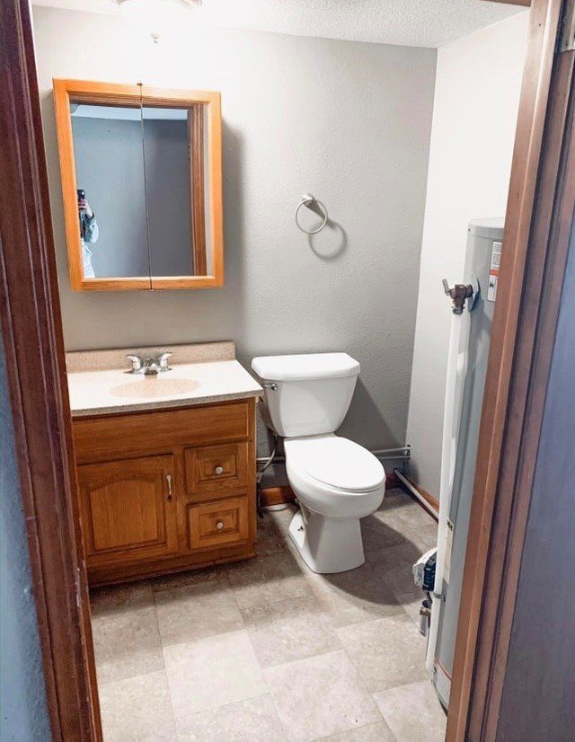 A bathroom with a toilet , sink and mirror.