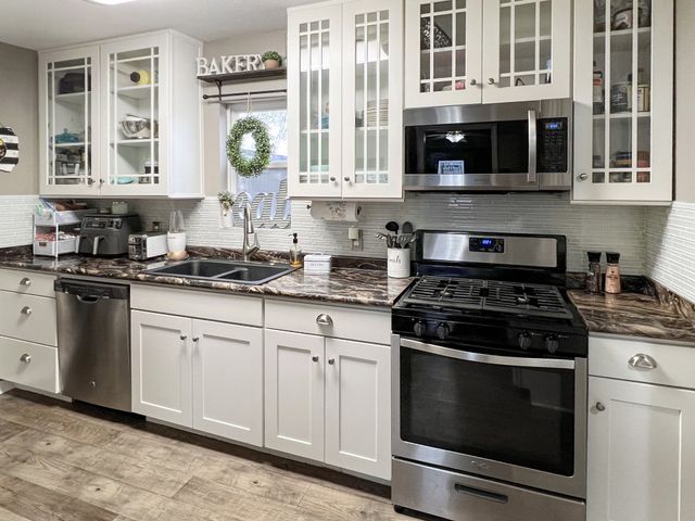 A kitchen with white cabinets , stainless steel appliances and granite counter tops.