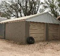 A garage with a tire on the ground in front of it.