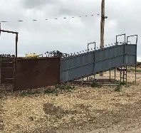 A large metal fence is sitting in the middle of a dirt field.