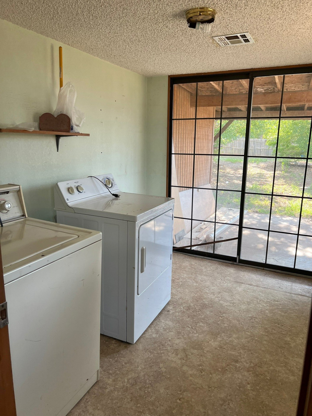 A laundry room with a washer and dryer and a sliding glass door.