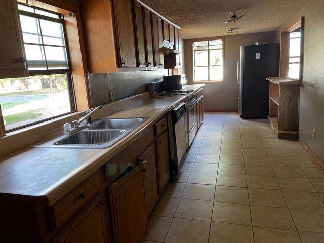 An empty kitchen with two sinks and a refrigerator