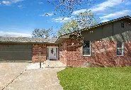 The front of a brick house with a garage and a driveway.