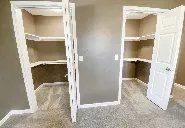 A walk in closet with two shelves and two doors.